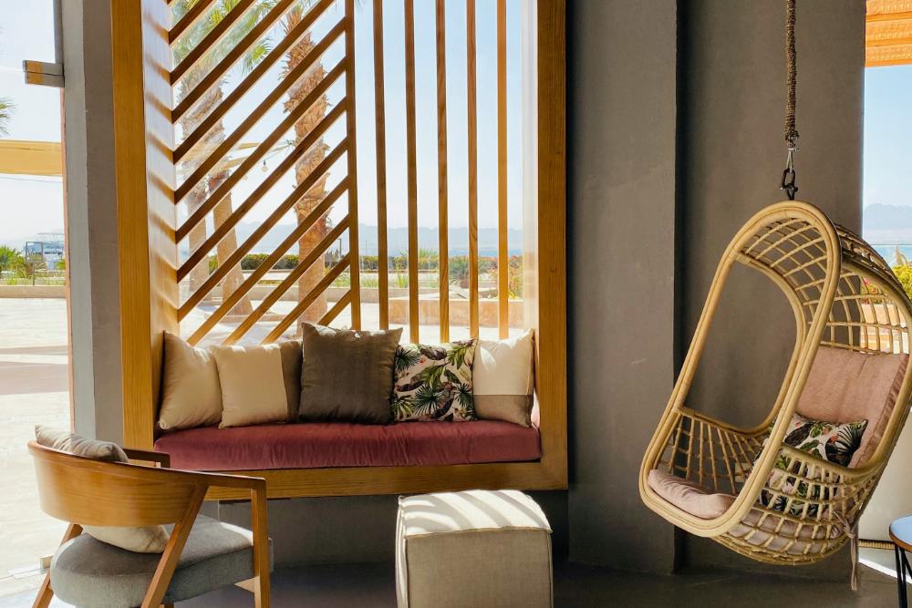 Moderne Terrasse mit roter Couch mit Holzelementen, Hängesessel auf Rattan, Mita-On GmbH